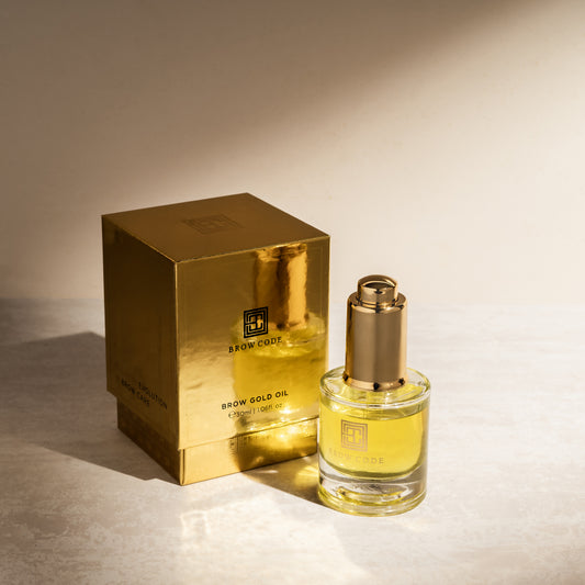 Eine goldene Brow Code-Dose steht neben einer Glasflasche mit Brow Gold Oil pflegendes Wachstumsöl, 30ml mit goldenem Tropfverschluss. Blashy Shop