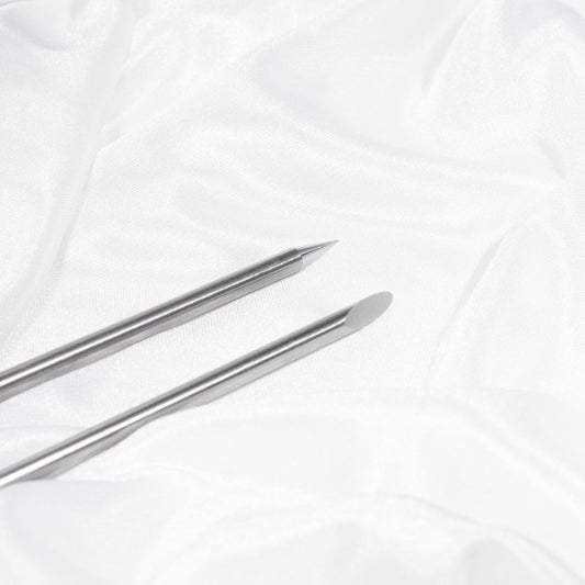 Das BWR Brow Tool - Mehrweg Edelstahl Wachsspatel von blashyshop.com ruht auf weißem, zerknittertem Stoff. Blashy Shop