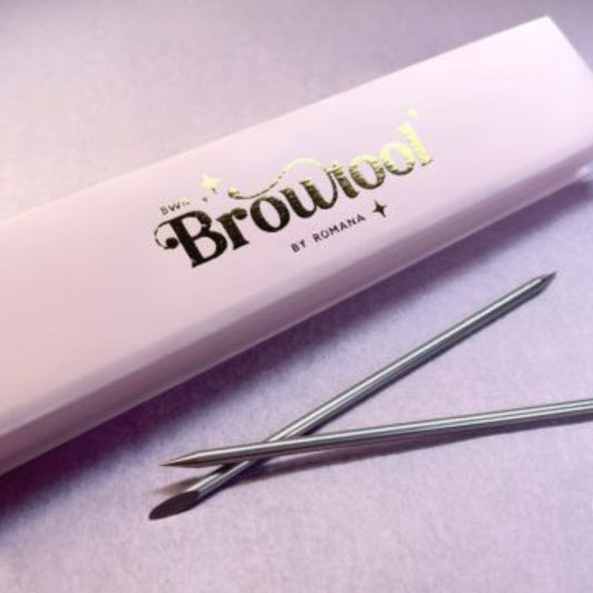 Eine rosa blashyshop.com Brow Tool Box und zwei BWR Edelstahl Wachsspatel ruhen auf einer hellvioletten Fläche. Blashy Shop