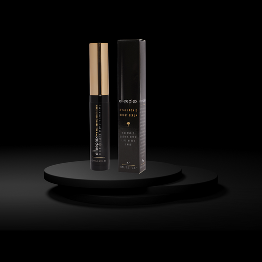 Ein schwarz-goldener Flakon von Elleebana Elleeplex Hyaluronic Boost Serum, 8 ml, steht neben seiner Verpackung auf einem schwarzen Podest. Blashy Shop