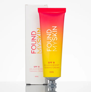 Eine Tube FOUND MY SKIN SPF 8 Melanin Boost Feuchtigkeitscreme, 100g, mit Verpackung im Hintergrund. Blashy Shop