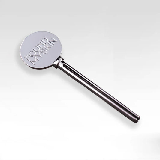 Das FOUND MY SKIN Tuben Squeezer Tool und der gravierte Metallspatel werden zusammen auf einem schlichten Hintergrund gezeigt. Blashy Shop