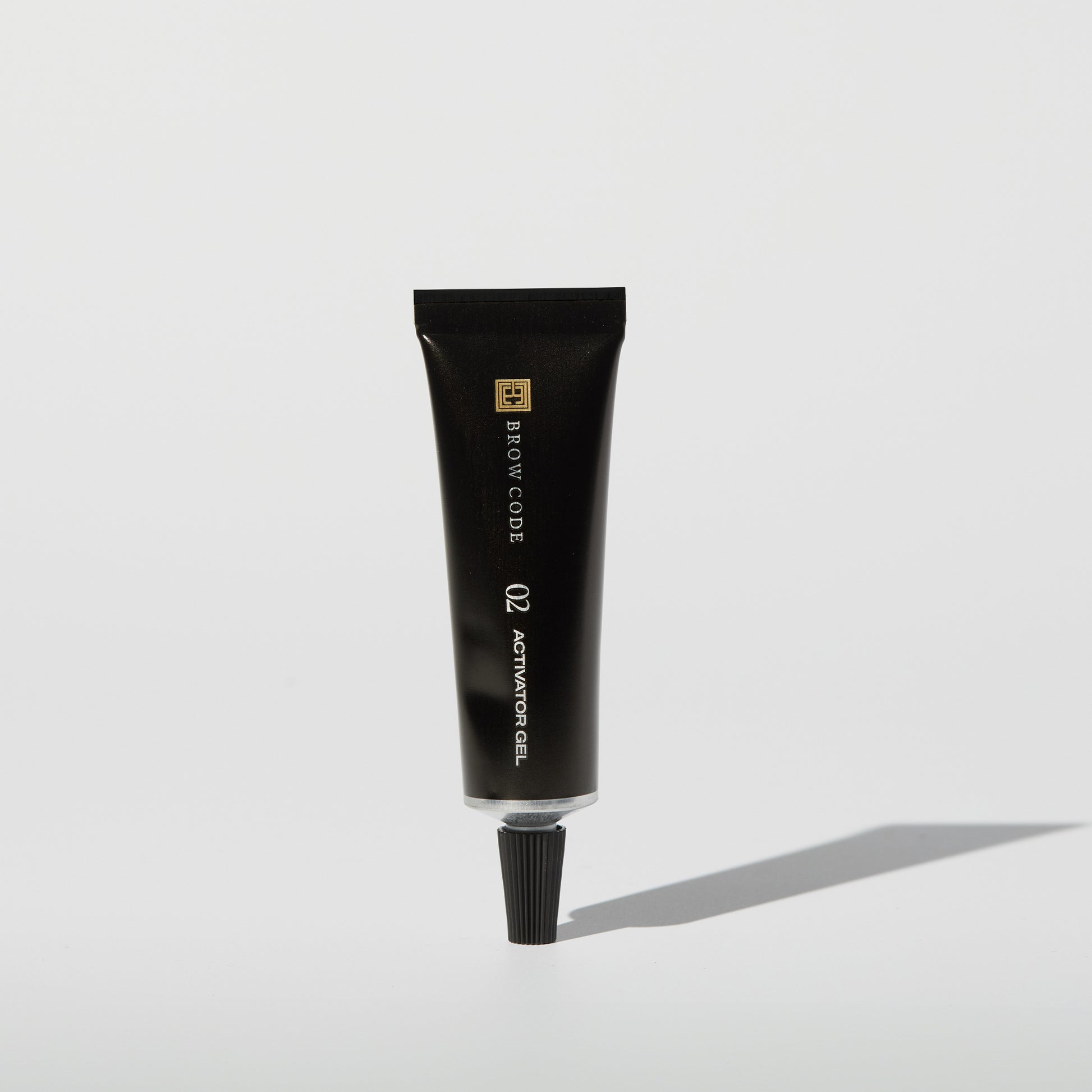 Eine schwarze Tube mit der Aufschrift Brow Code Gel Augenbrauenfarbe, PPD frei, 15ml steht aufrecht auf einer weißen Fläche mit einem Schatten. Blashy Shop