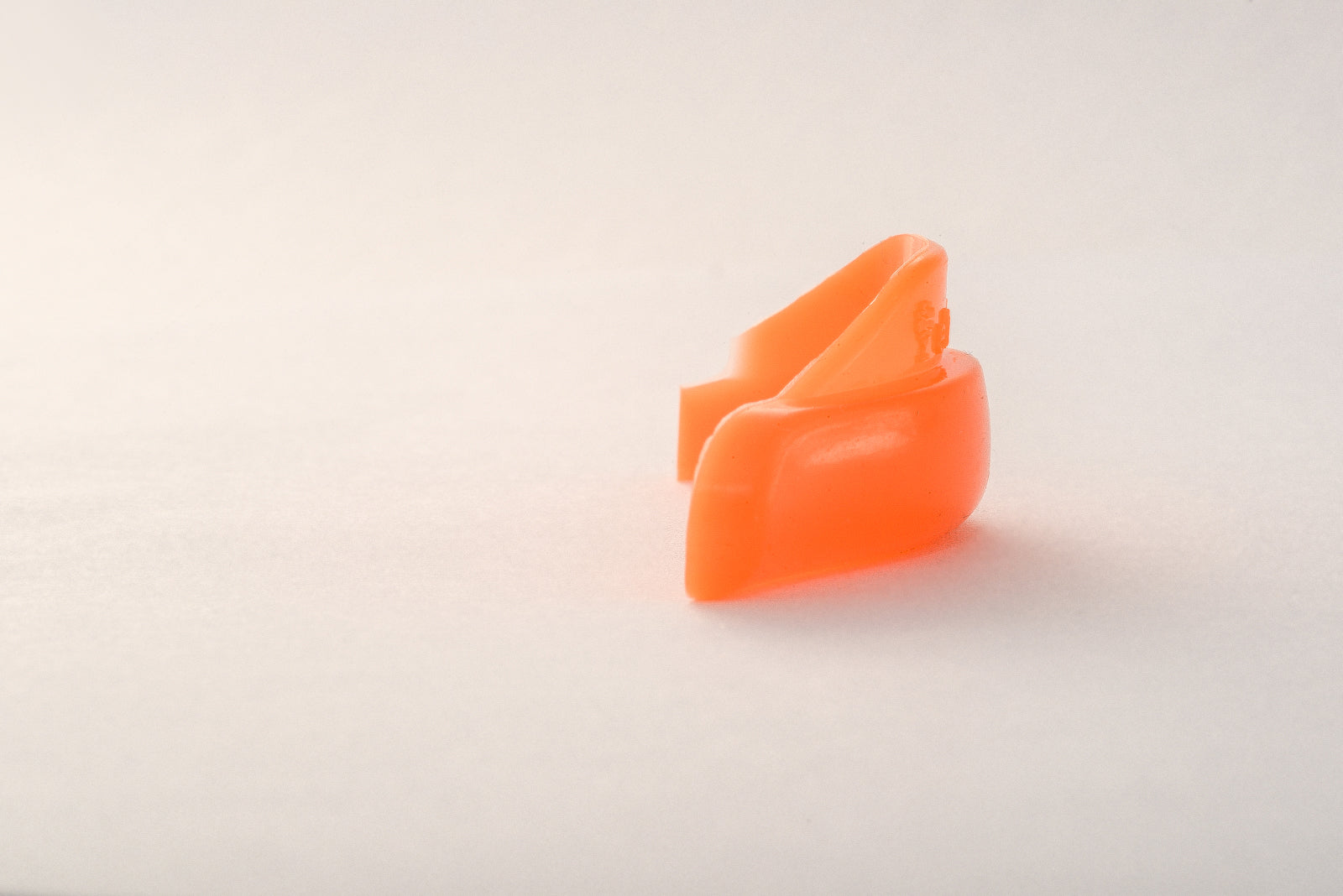 Ein einzelner orangefarbener Schaumstoff-Ohrstöpsel auf weißem Grund, geformt wie Elleebana Flex Hybrid Shields - Kombi Lift L-Curl (S-XL). Blashy Shop