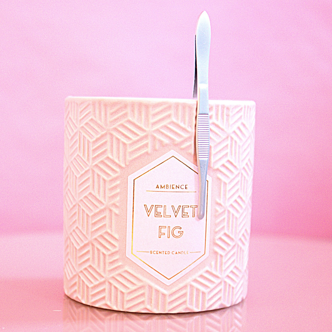 Eine weiß strukturierte Velvet Fig Kerze mit einer Blashy EASY TWEEZY Augenbrauen-Pinzette - rund ruht auf einem rosa Hintergrund. Blashy Shop